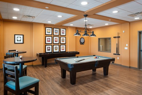A billiards room with a pool table and a table and chairs.