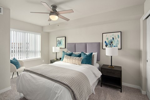 A bedroom with a bed, nightstand, and a ceiling fan.