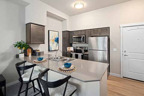 A kitchen with a white counter top and black chairs.