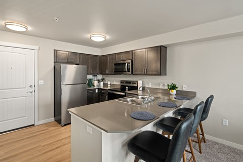 A kitchen with a refrigerator, sink, and stove.