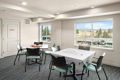 A conference room with a table and chairs and a window overlooking a parking lot.