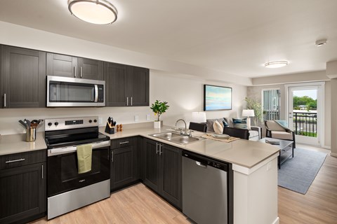 A modern kitchen with dark wood cabinets and stainless steel appliances.