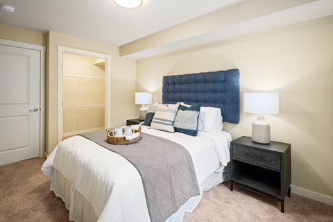 A bedroom with a bed, nightstand, and lamp.