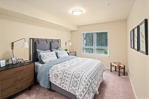A bedroom with a large bed and a window with blinds.