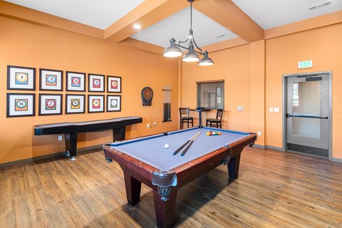 A pool table in a room with orange walls and a bench.
