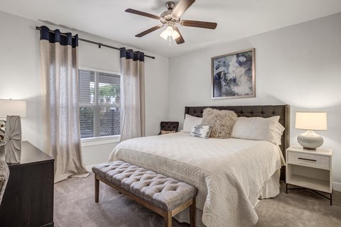 A bedroom with a bed, nightstand, and a ceiling fan.