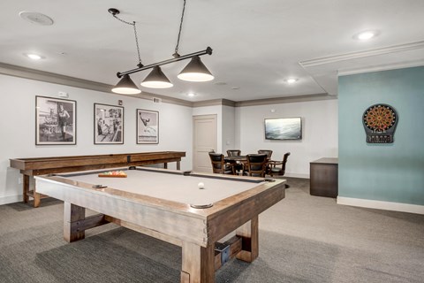 A pool table is in the middle of a room with a light blue wall and a chair.