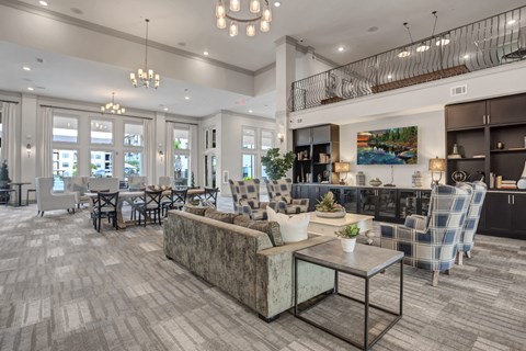 A spacious living room with a grey sofa and a glass coffee table.