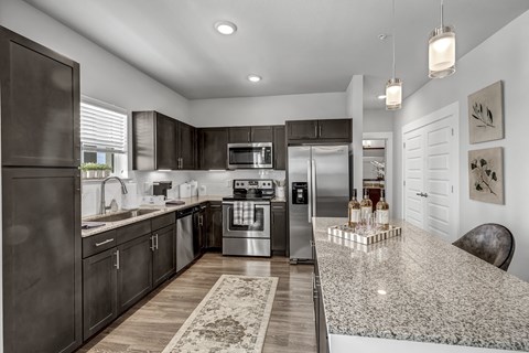 A modern kitchen with dark brown cabinets and stainless steel appliances.