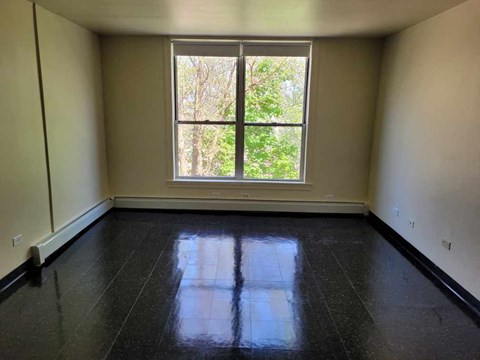 A room with a large window and black floor tiles.