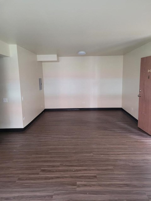 A room with wooden floors and a door on the right.