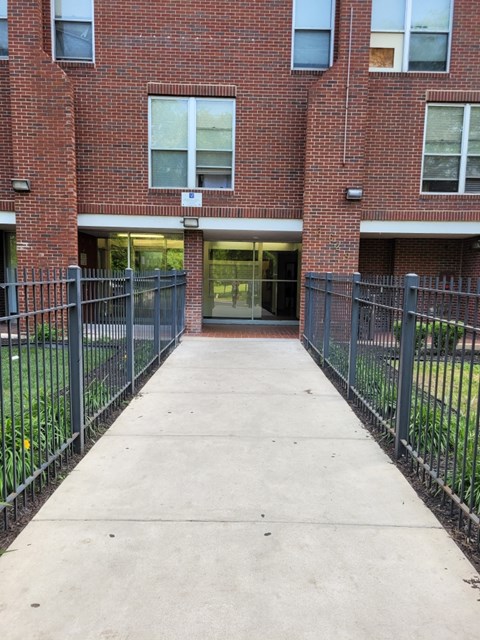 A brick building with a black fence and a concrete walkway.