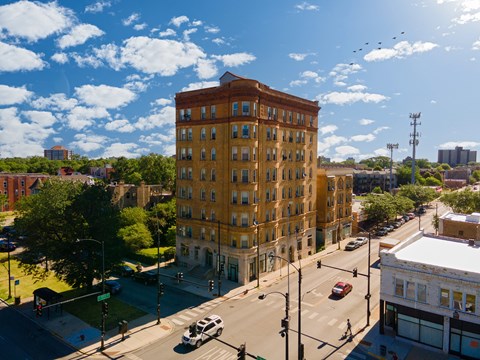 A large yellow building is in the middle of a street with cars and traffic lights.