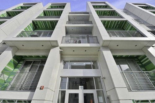 A modern white building with green stripes on the balconies.