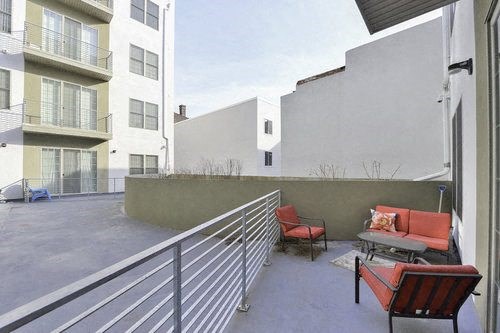 A balcony with a table and chairs overlooks a parking lot.