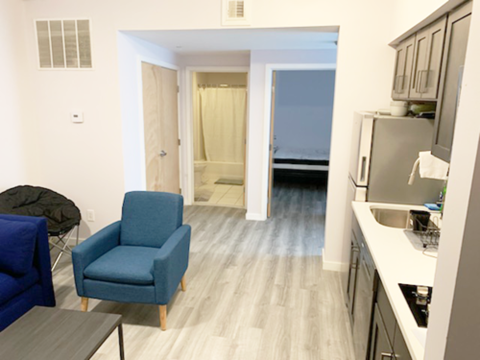 A blue chair sits in a kitchen with a sink and a window.