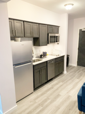 A kitchen with a refrigerator, microwave, and cabinets.