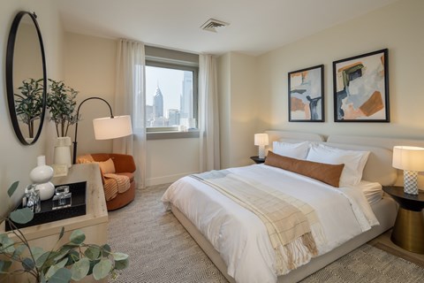 A well-lit bedroom with a large bed and a view of the city.