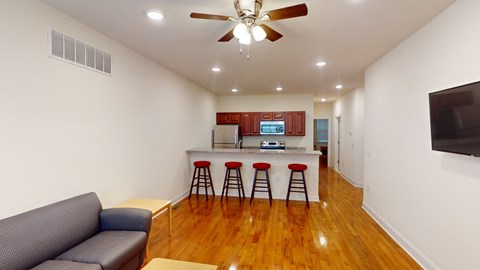 A living room with a grey couch and a bar area with stools.