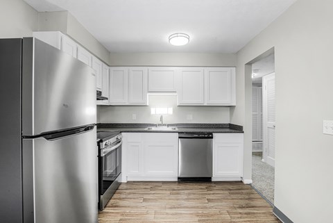 A modern kitchen with white cabinets and a stainless steel refrigerator.
