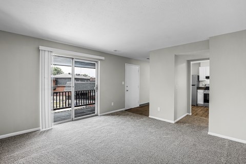 A spacious living room with a sliding glass door leading to a balcony.