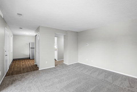 A spacious room with a carpeted floor and white walls.