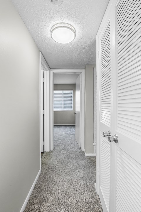 A long white hallway with a carpeted floor and white walls.