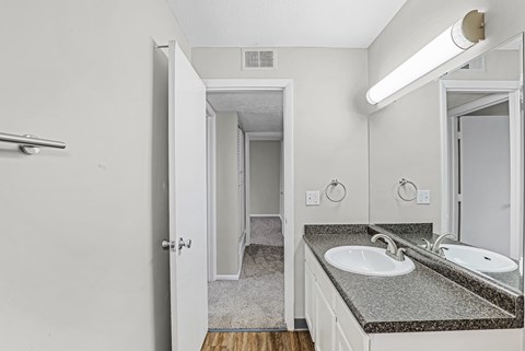 A bathroom with a sink, mirror, and a door.