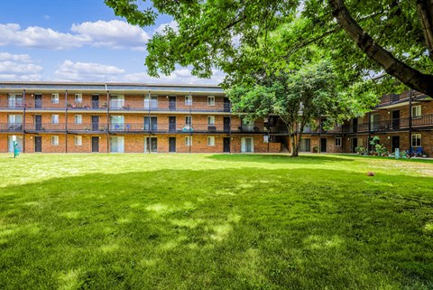 A large grassy area in front of a building with trees.