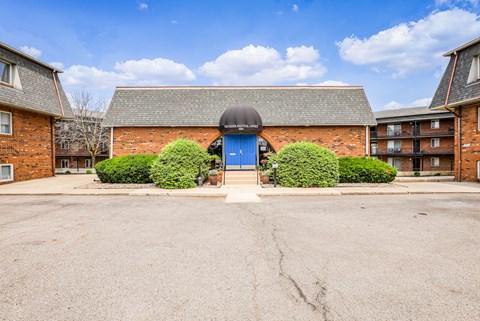 A blue door is the centerpiece of a brick building.