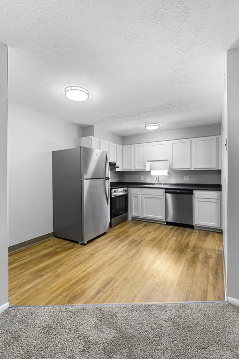 A kitchen with a refrigerator, cabinets, and a counter.