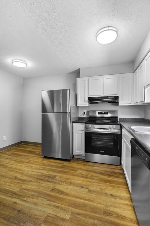 A kitchen with a stainless steel refrigerator and wooden floors.