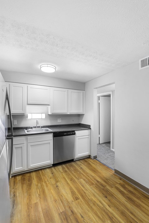 A kitchen with white cabinets and a wooden floor.