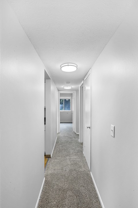 A long hallway with a carpeted floor and white walls.