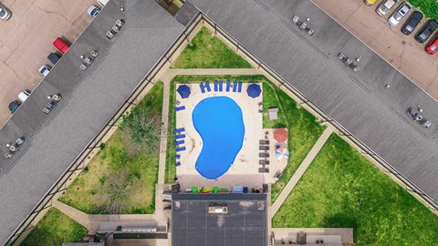 A small pool with a slide in the middle of a grassy area.