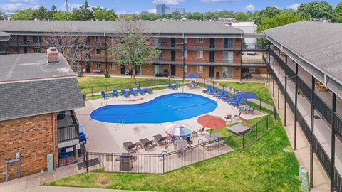 A pool surrounded by chairs and umbrellas in a grassy area.