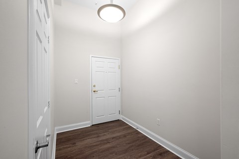 a bedroom with white walls and a white door and a wooden floor
