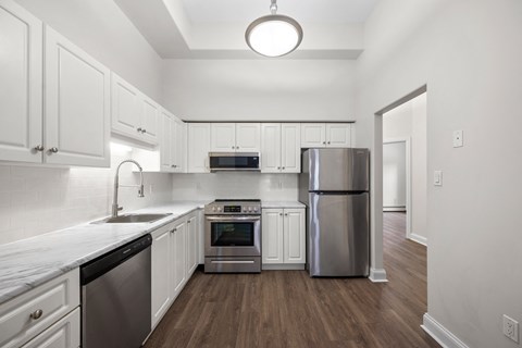 an empty kitchen with white cabinets and stainless steel appliances
