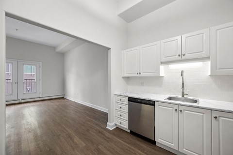 an empty kitchen with white cabinets and a stainless steel dishwasher