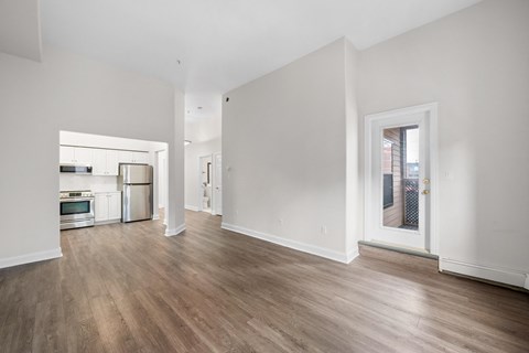 a living room and kitchen with white walls and wood flooring