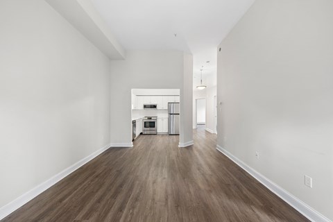 a living room and kitchen with white walls and wood floors