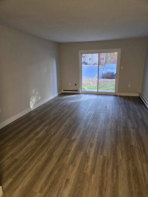 a living room with a wood floor and a door to a patio