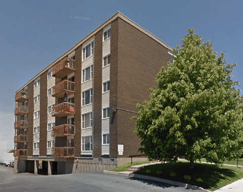 a brick apartment building with a tree in front of it