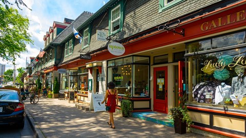 A woman in a red dress is walking down a street past a storefront with a sign that says "GALLE".