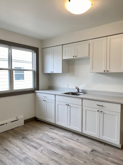 A kitchen with white cabinets and a window.