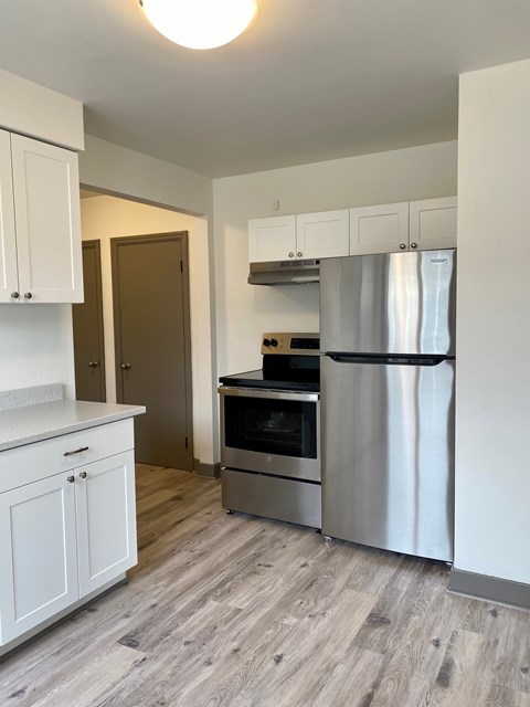 A kitchen with a stainless steel refrigerator, oven, and cabinets.