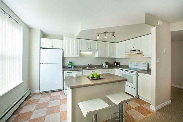 a white kitchen with a counter and a refrigerator