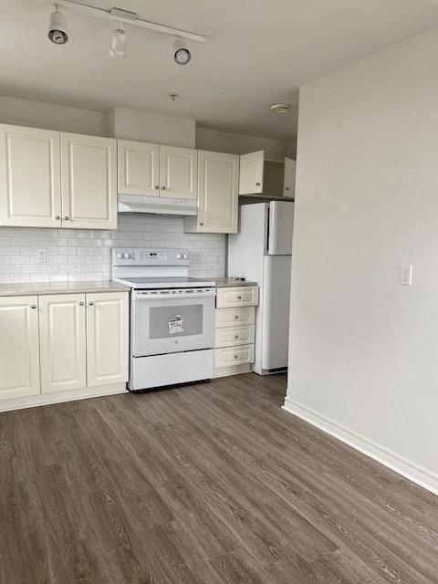 an empty kitchen with white cabinets and a stove