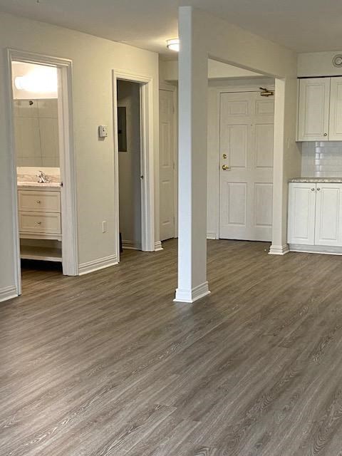 an empty living room with a wood floor and a bathroom