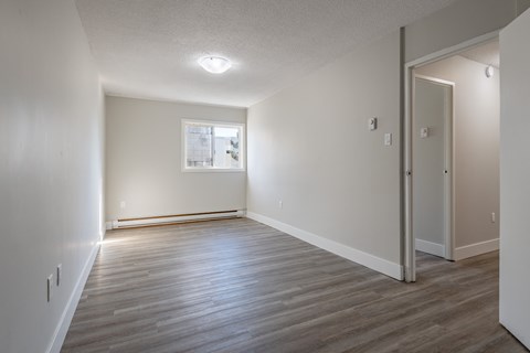 an empty living room with wood flooring and a window
